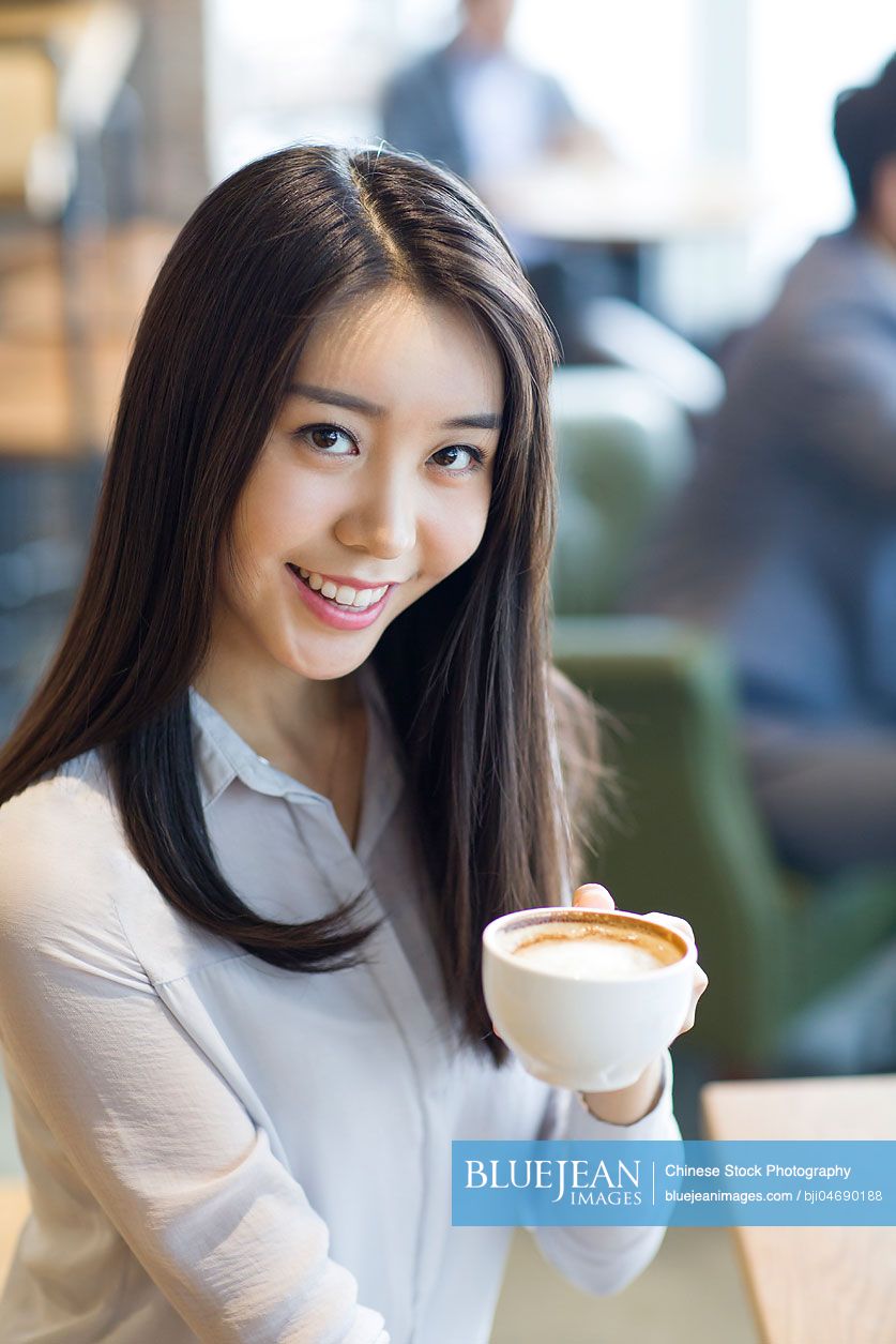 Young Chinese woman drinking coffee in café