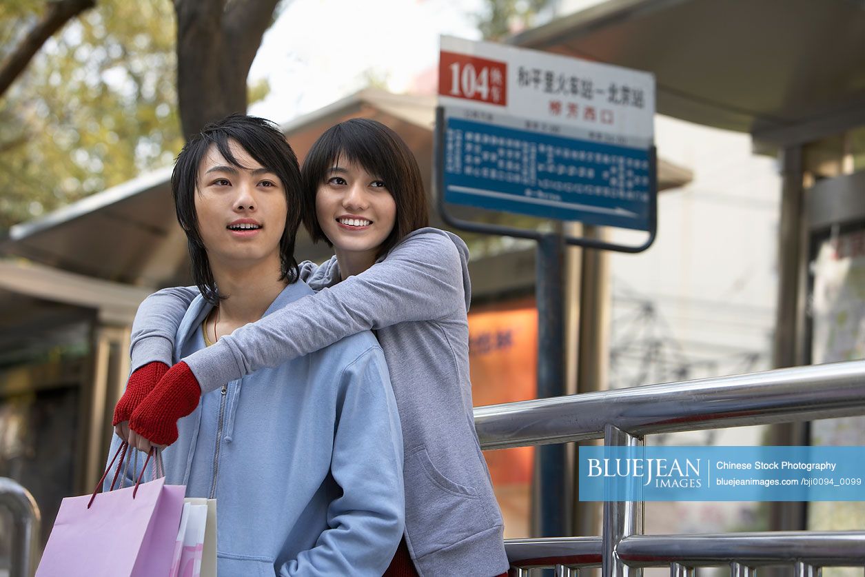 Young Chinese couple waiting at a bus station