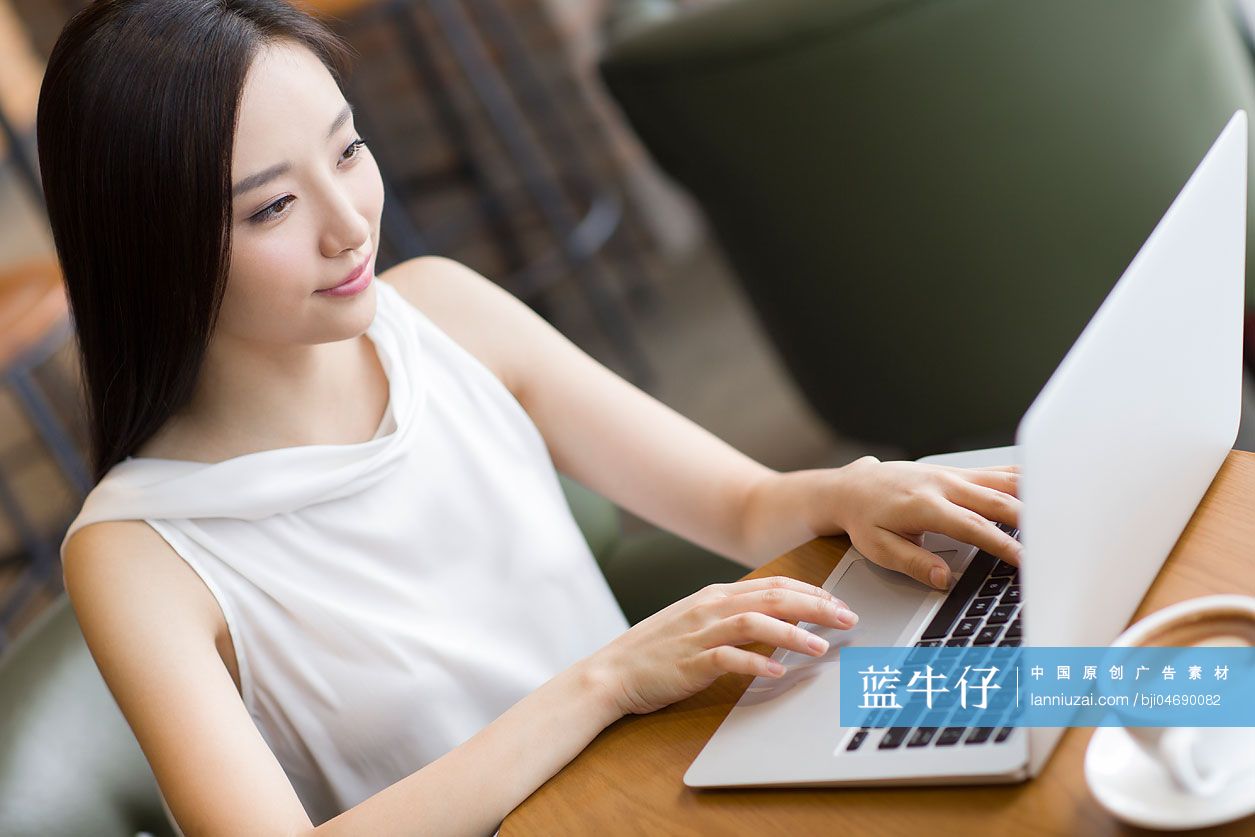 年轻女士在咖啡厅使用笔记本电脑工作