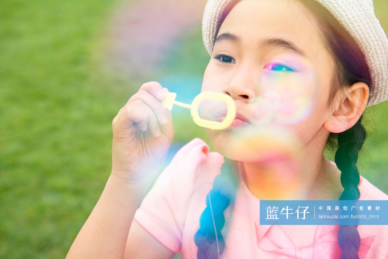 小女孩在草地上吹泡泡