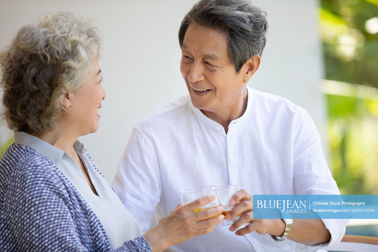 Happy senior Chinese couple relaxing on balcony