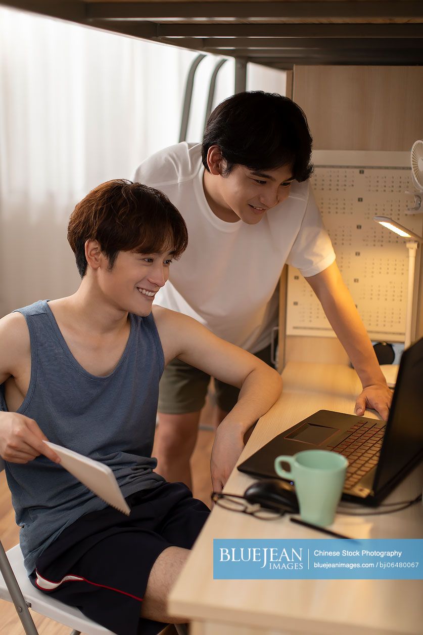 Young Chinese university students using laptop in dormitory