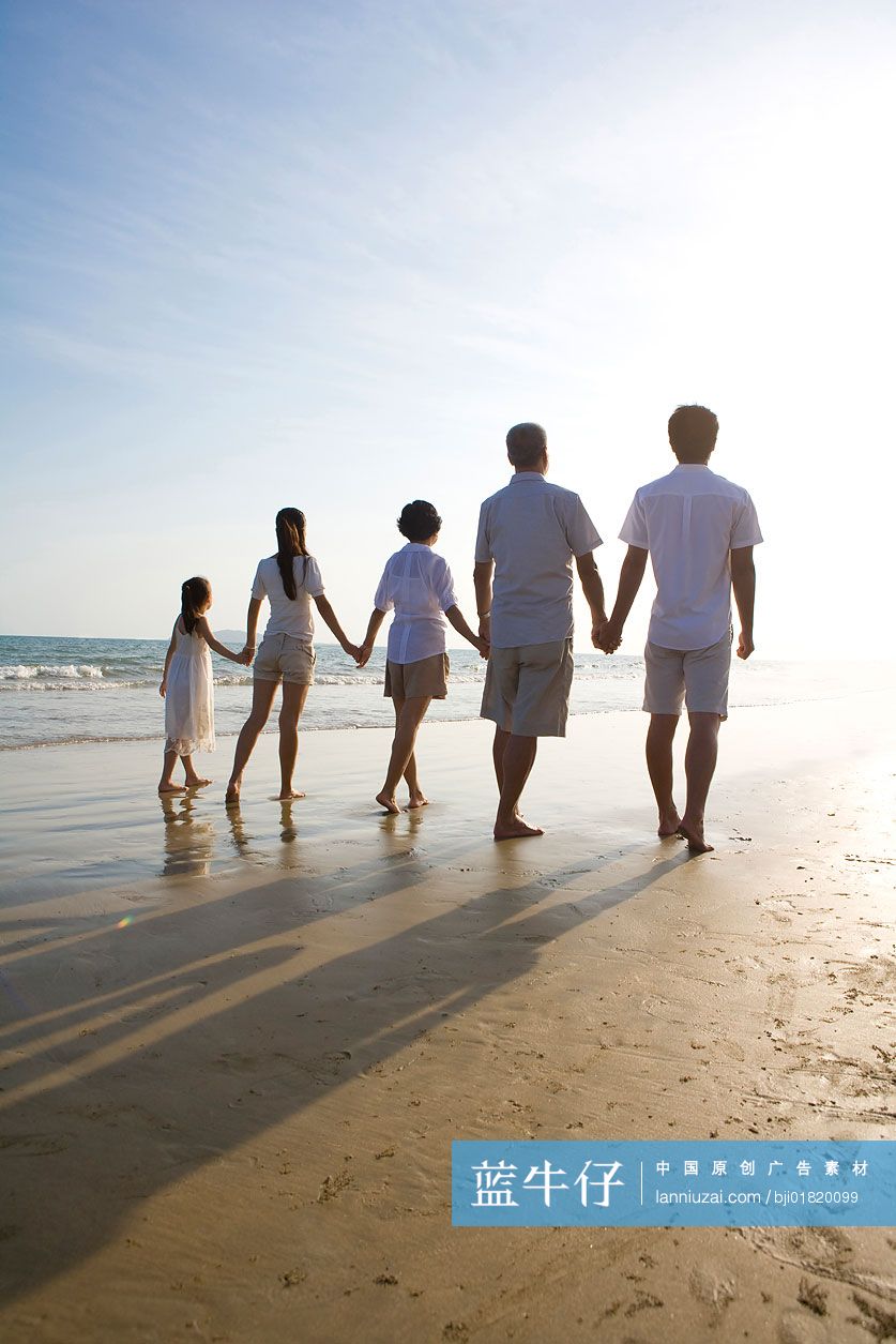 全家人手拉手在沙滩上散步