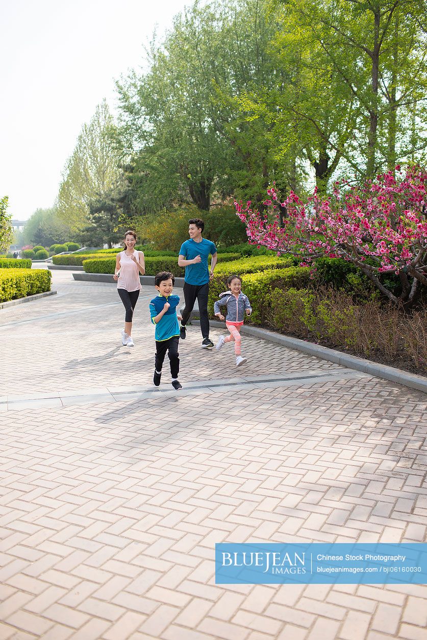 Happy young Chinese family running in park