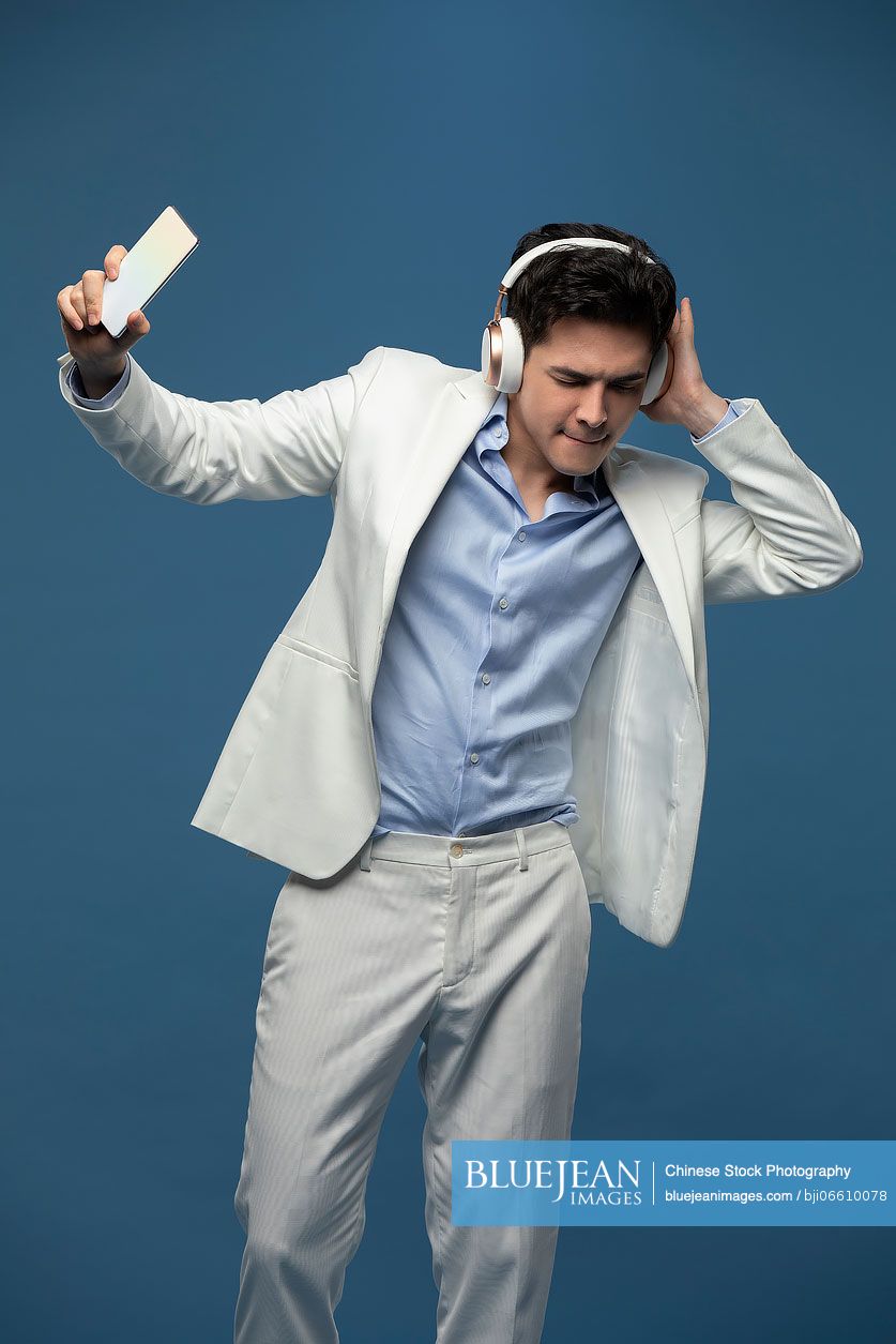 Studio shot of fashionable young Chinese man listening to music