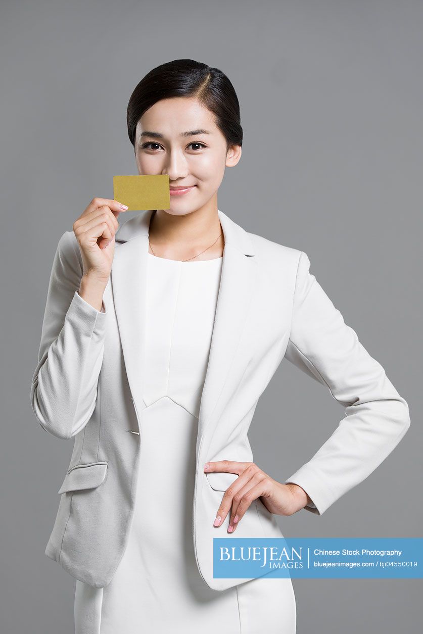 Happy young Chinese businesswoman holding a credit card