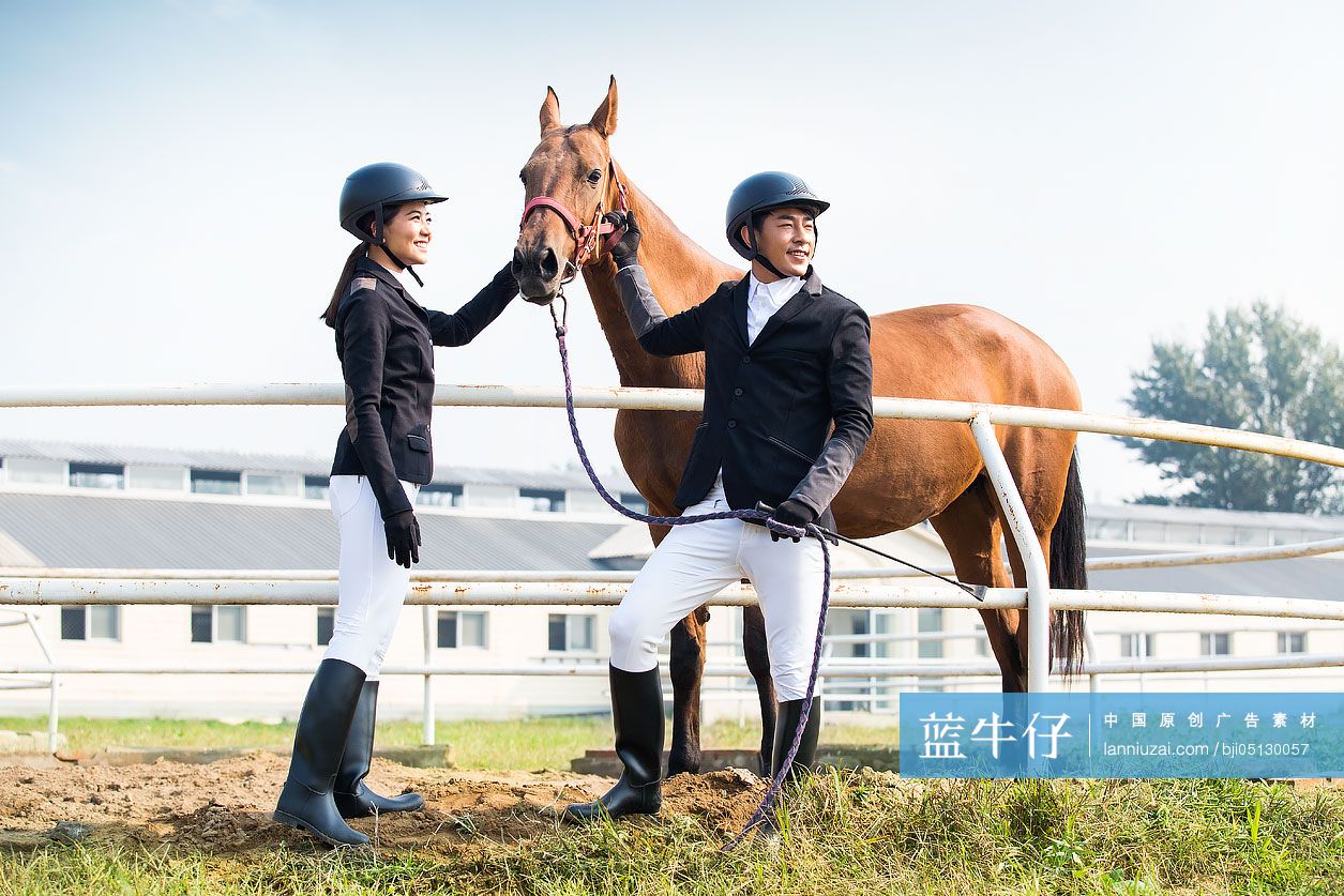 快乐的年轻情侣牵着马