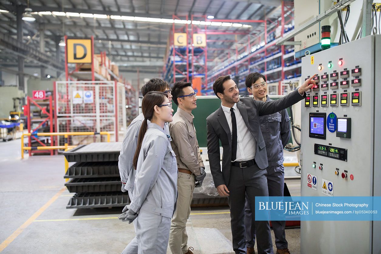 Businessman and engineers checking machine in the factory