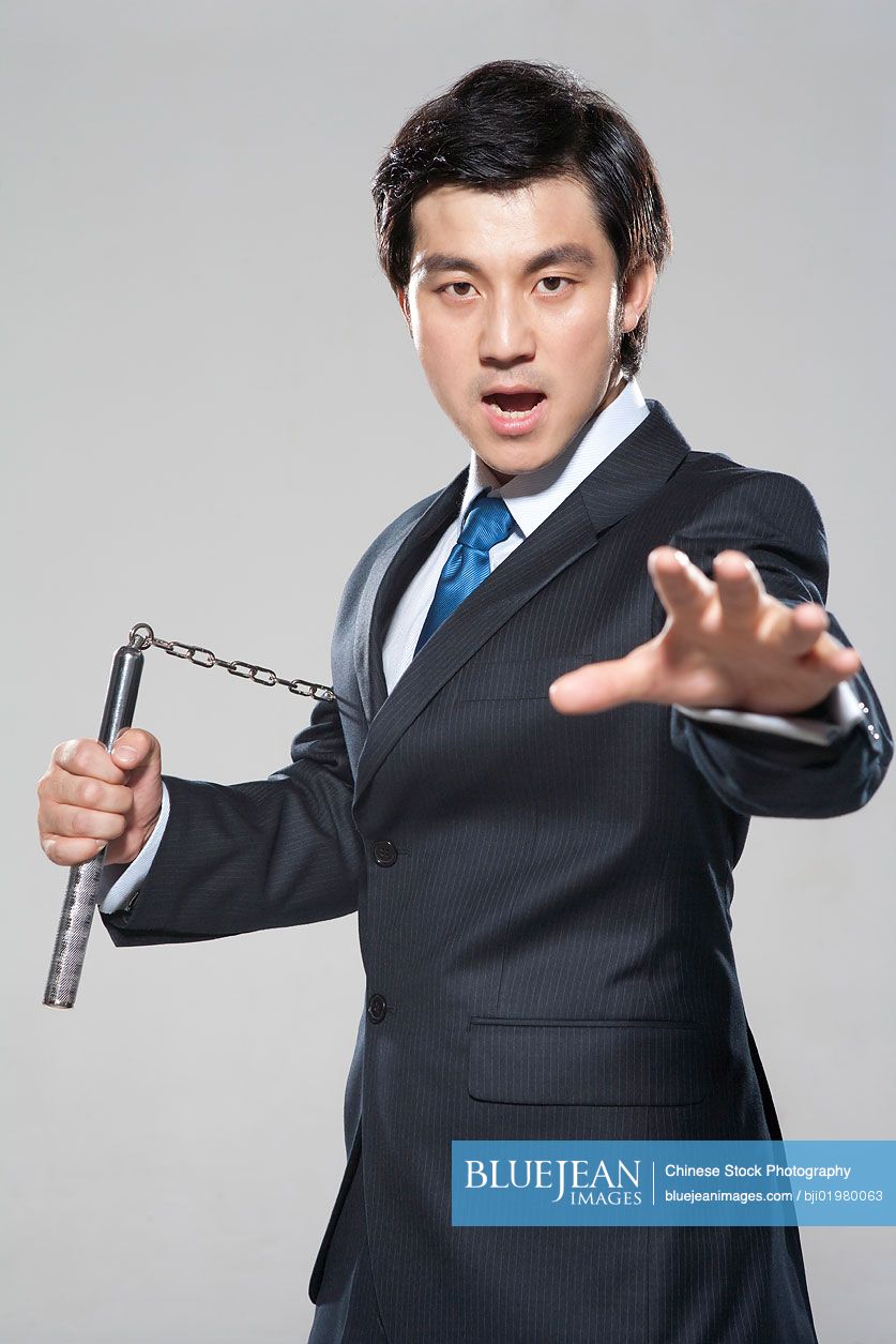 Chinese businessman holding nunchukas on white background