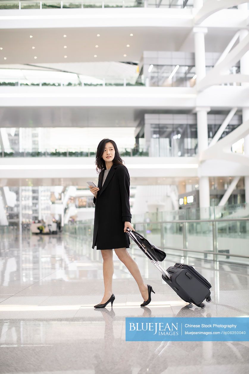 Young Chinese businesswoman with luggage at airport