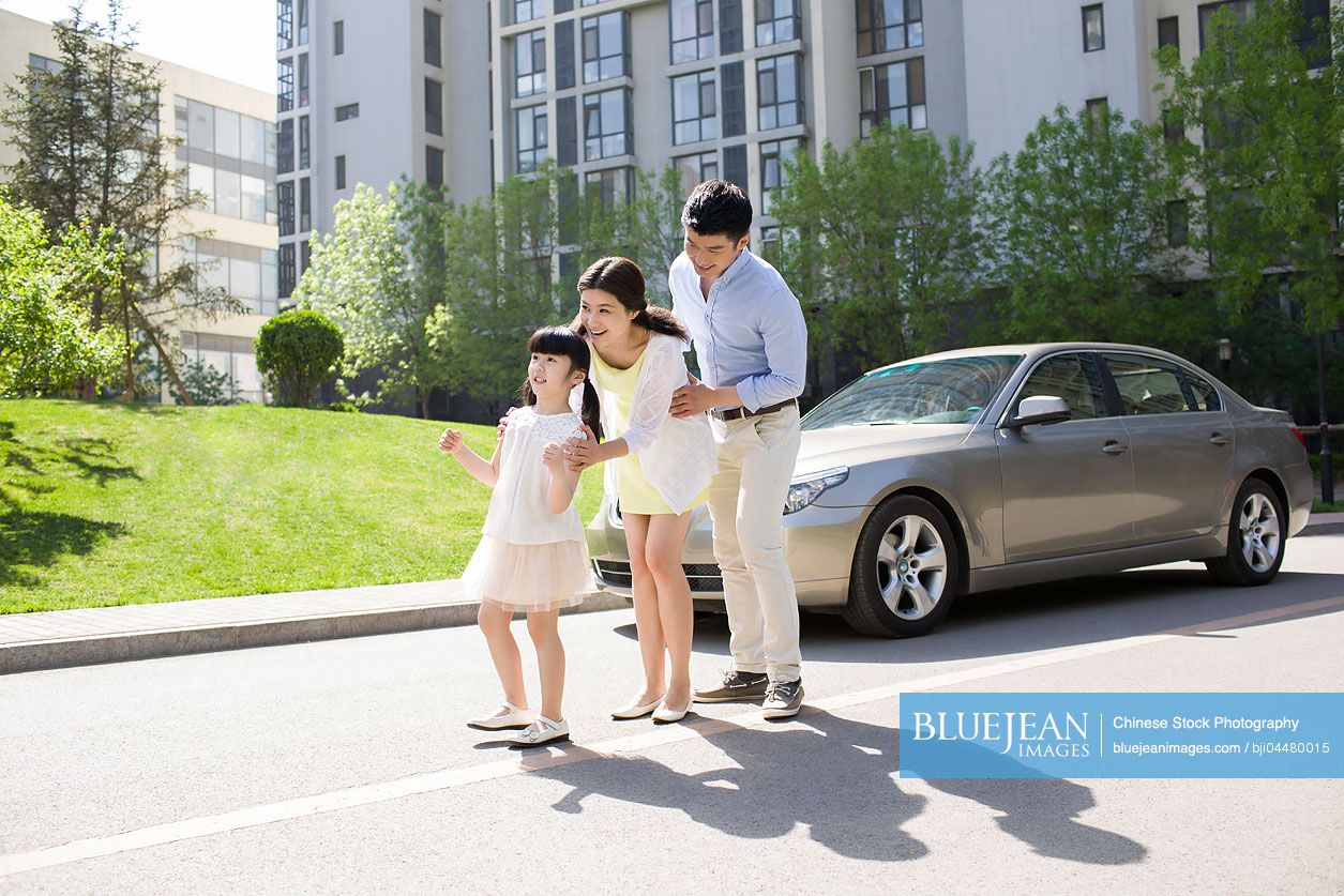Happy young Chinese family and car