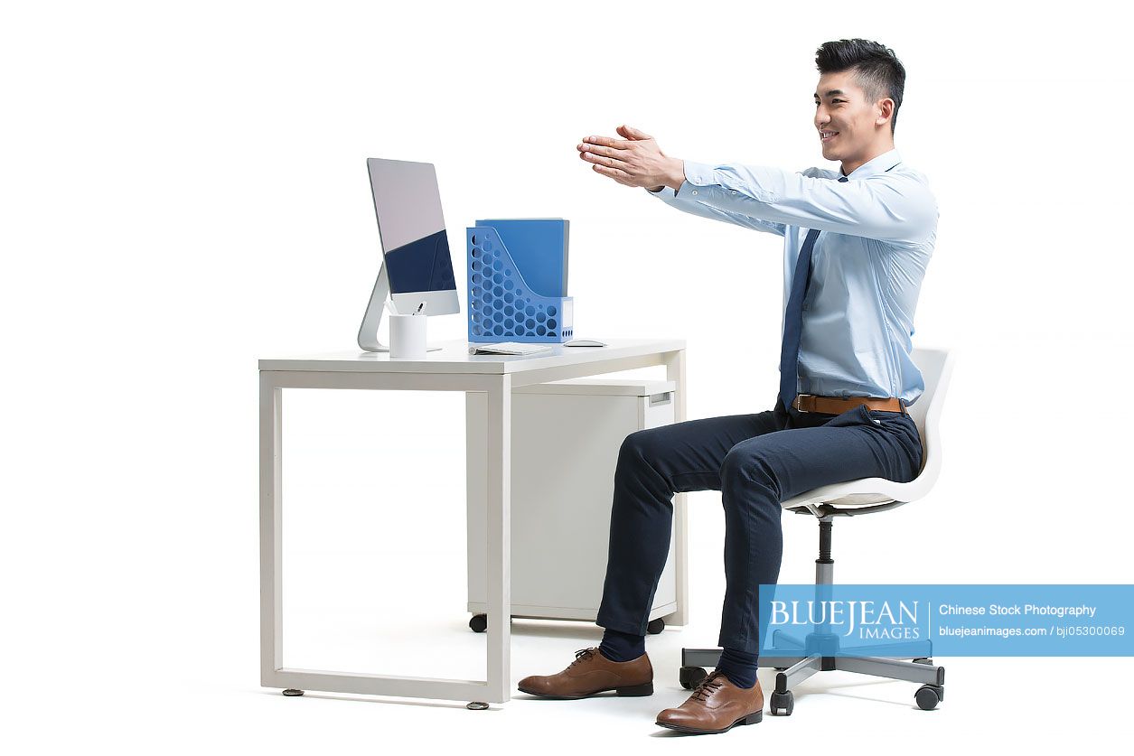 Young Chinese businessman exercising in office