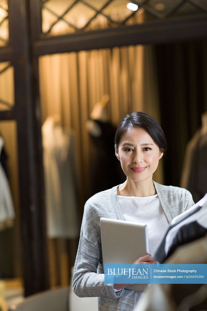 Chinese clothing store owner with digital tablet