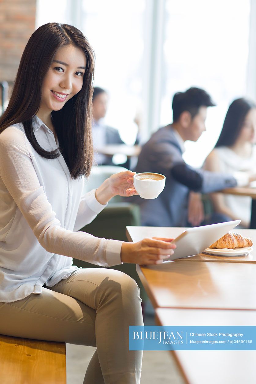 Young Chinese woman using digital tablet in café