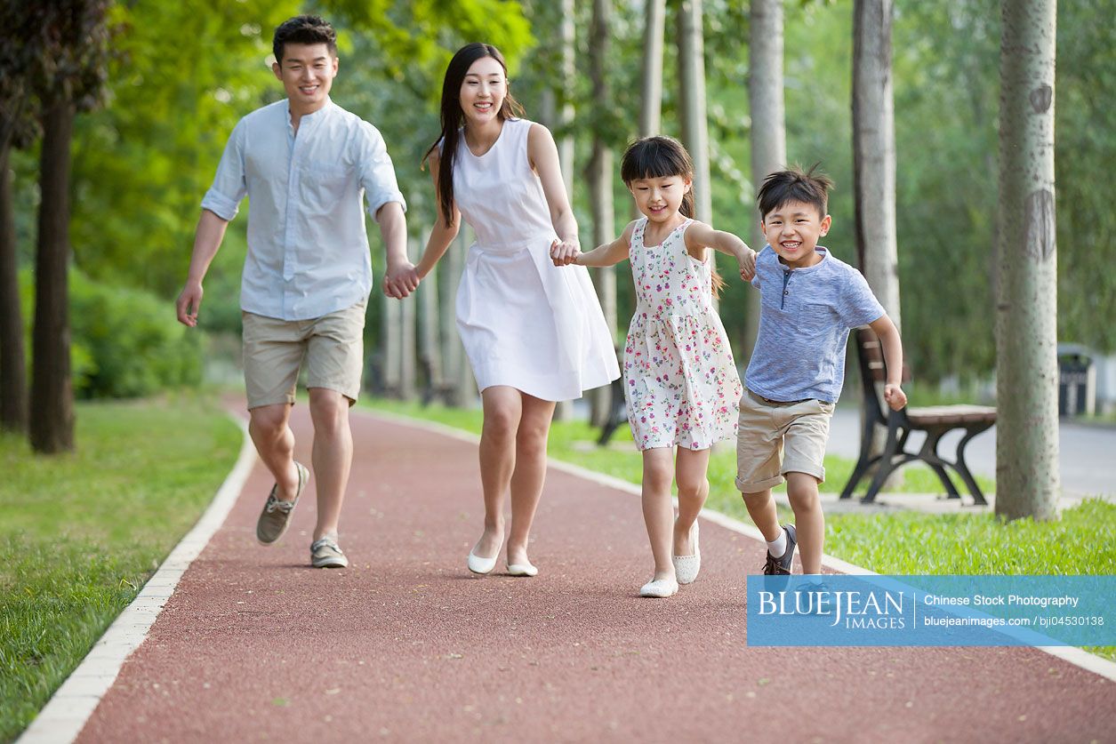 Happy young Chinese family running in park