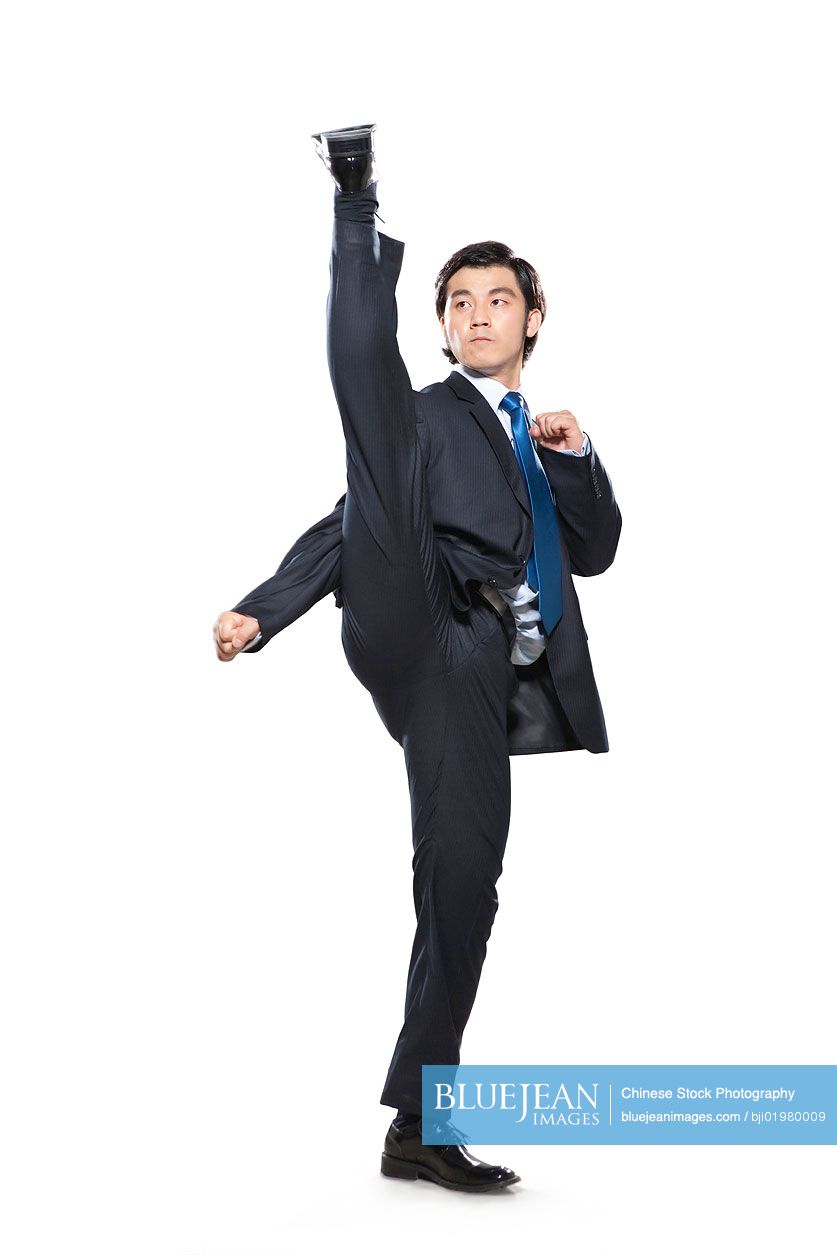 Chinese businessman fighting stance with leg in the air