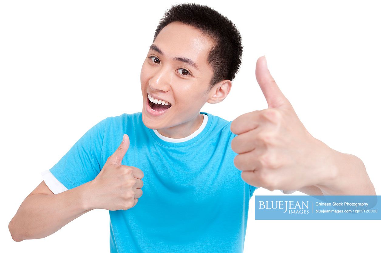 Cheerful young Chinese man doing thumbs up