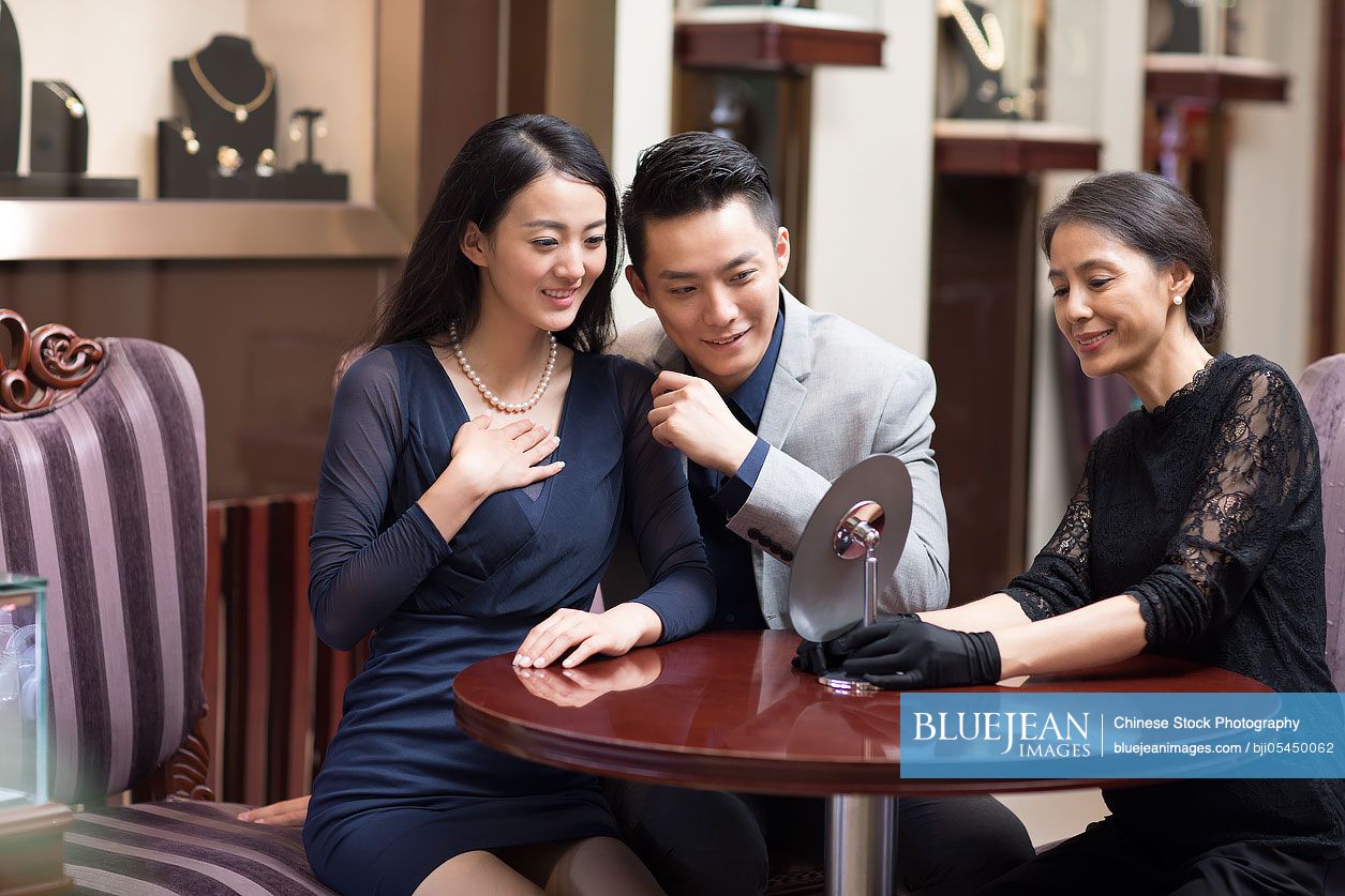 Happy Chinese young couple shopping in jewelry store 