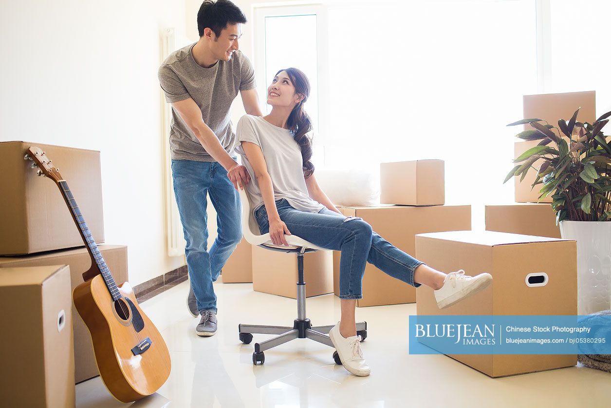 Happy young Chinese couple moving to a new house