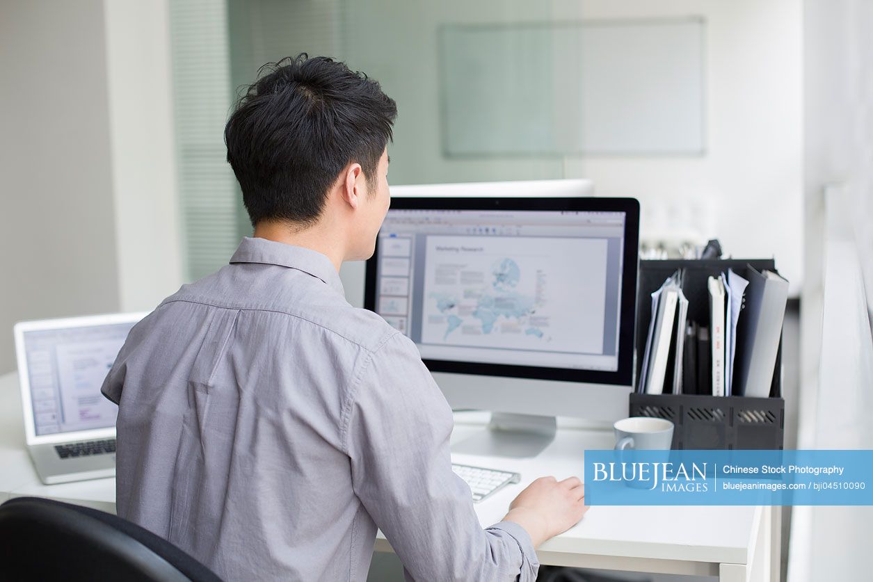 Young Chinese businessman using computer in office