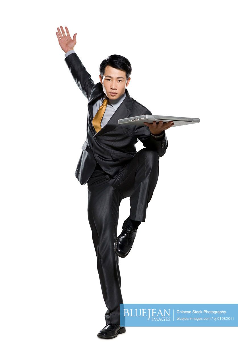 Chinese businessman in fighting stance holding laptop