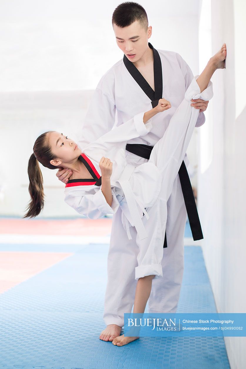 Young Chinese instructor teaching girl Tae Kwon Do