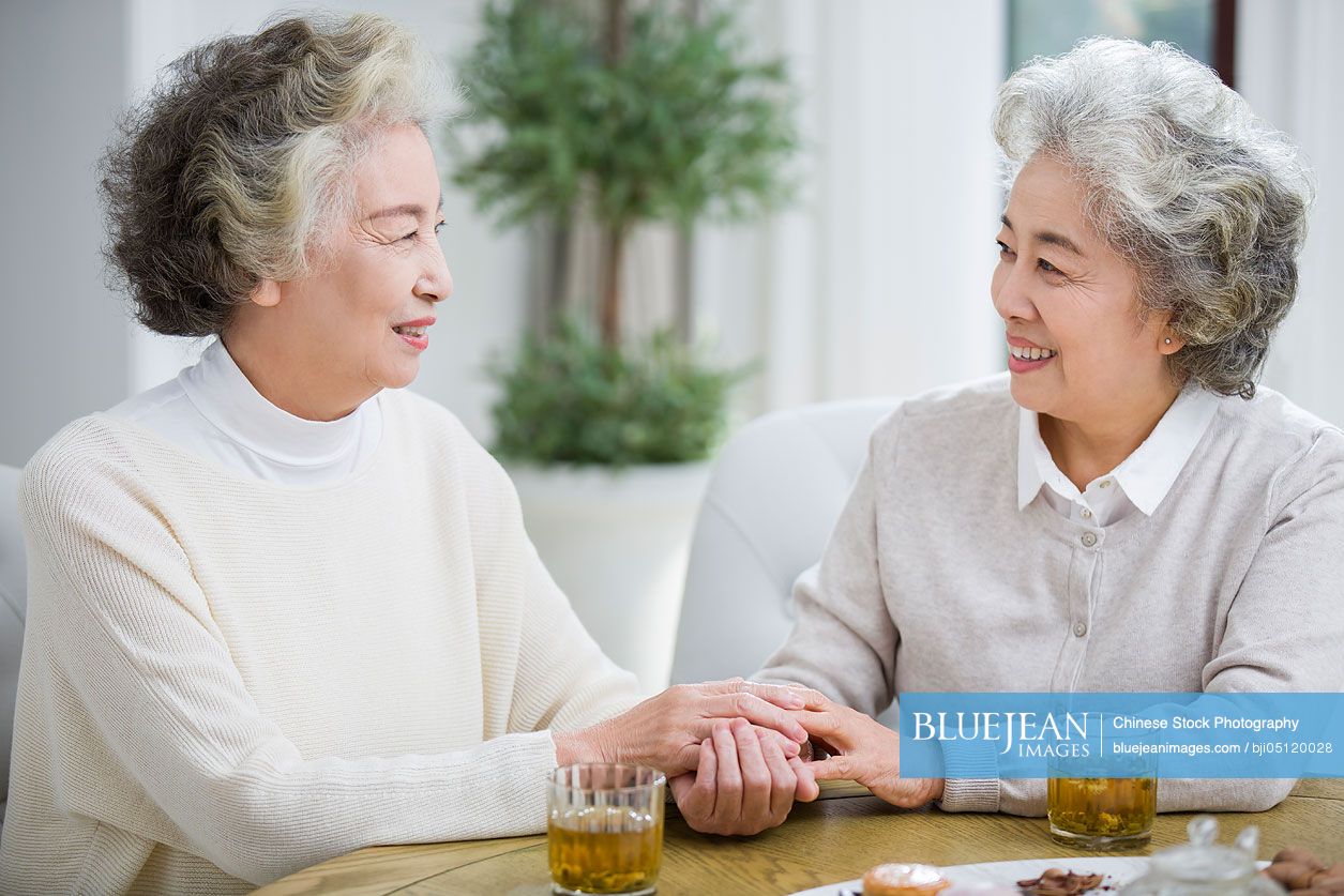 Happy senior Chinese women talking and drinking tea