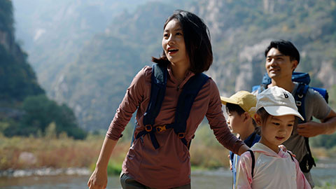 Happy young Chinese family hiking outdoors