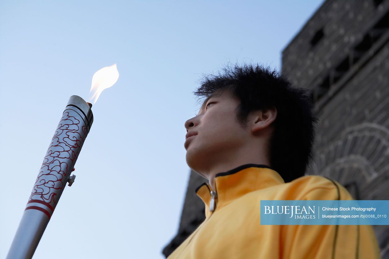 Young Chinese man holding Olympic torch at the UNESCO world heritage site