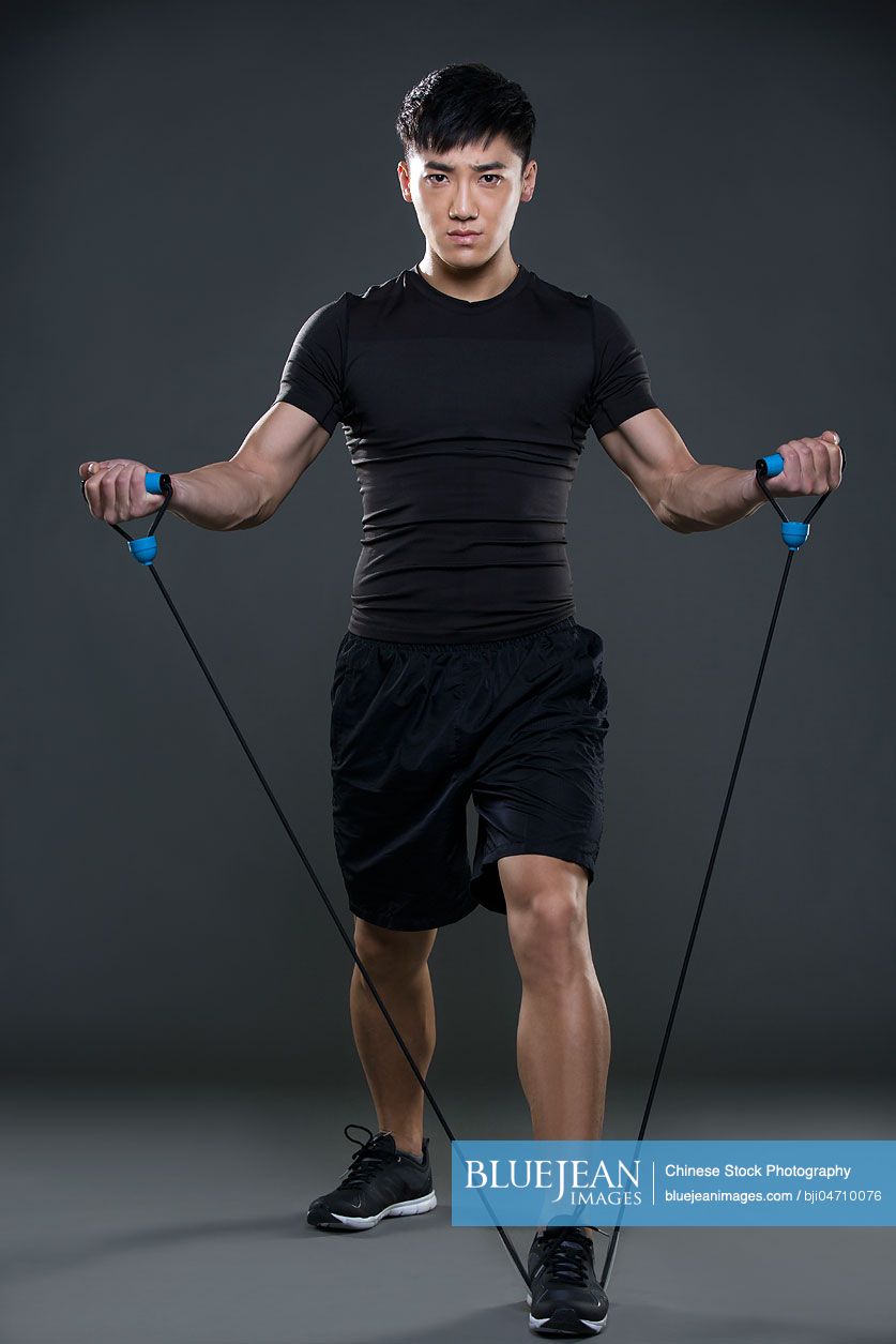 Young Chinese man exercising with resistance band