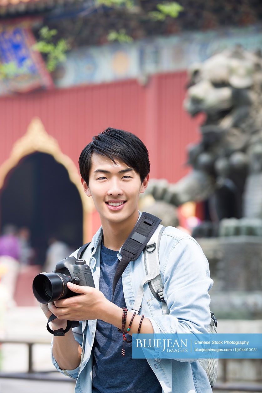 Young Chinese man travelling at the Lama Temple with camera
