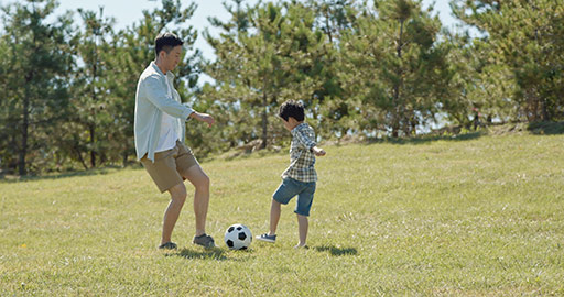 Happy Chinese father and son playing football in park,4K