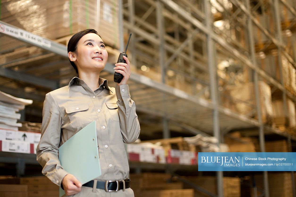 Male Chinese warehouse worker with clipboard