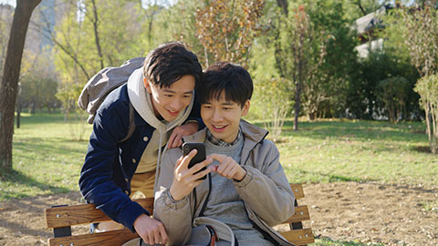 Happy Chinese college boys using smart phone