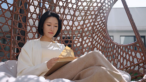 Happy young Chinese woman reading on hanging-chair,4K