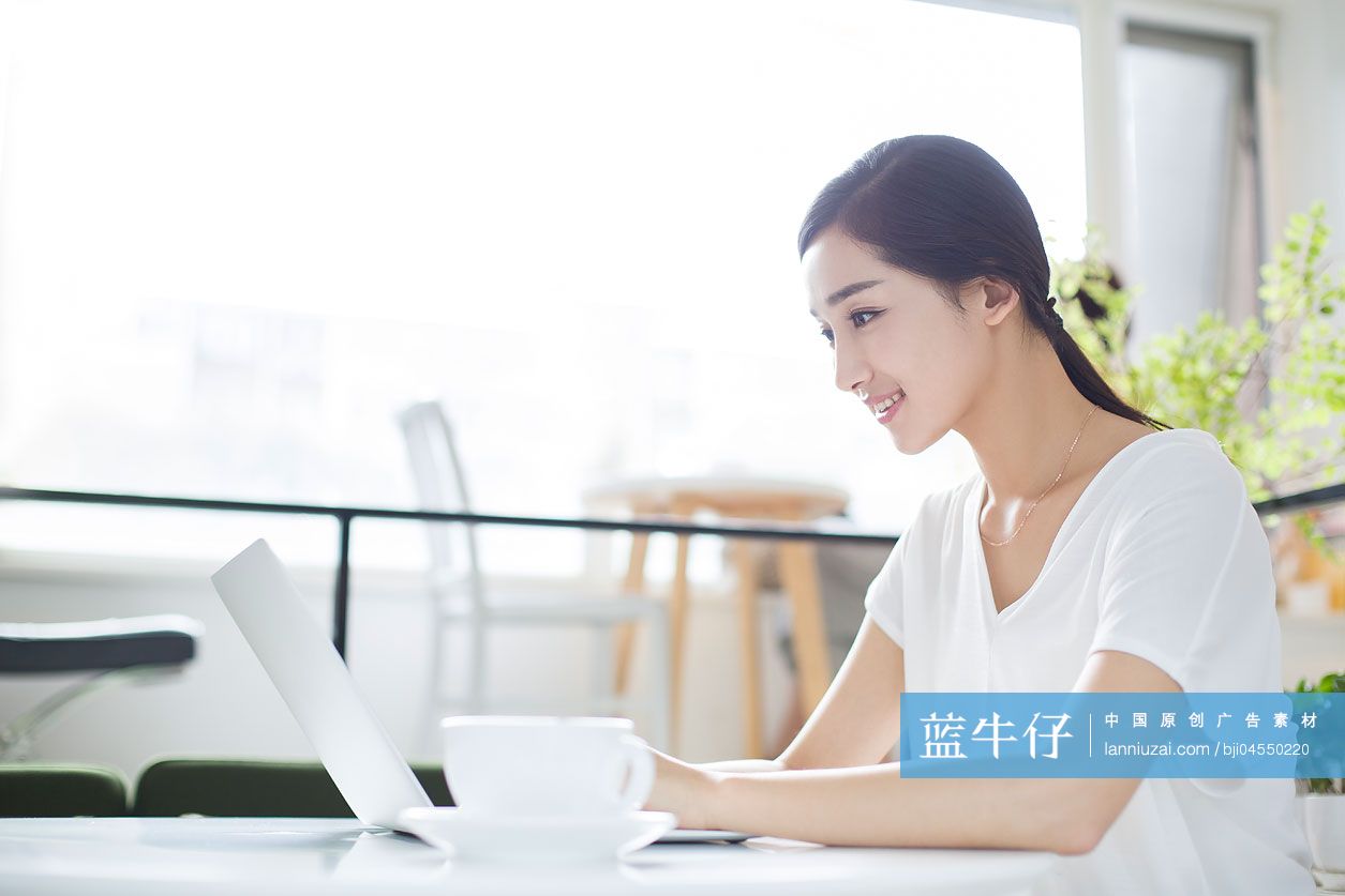 快乐的年轻女子在咖啡店使用笔记本电脑