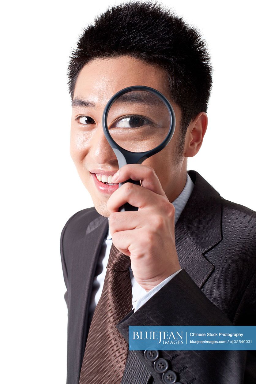 Portrait of a businssman looking through magnifying glass