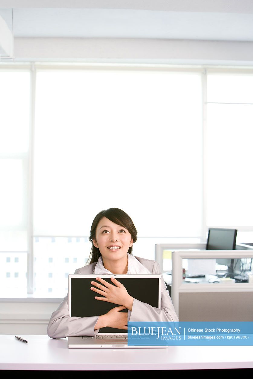 Chinese office worker hugging her computer