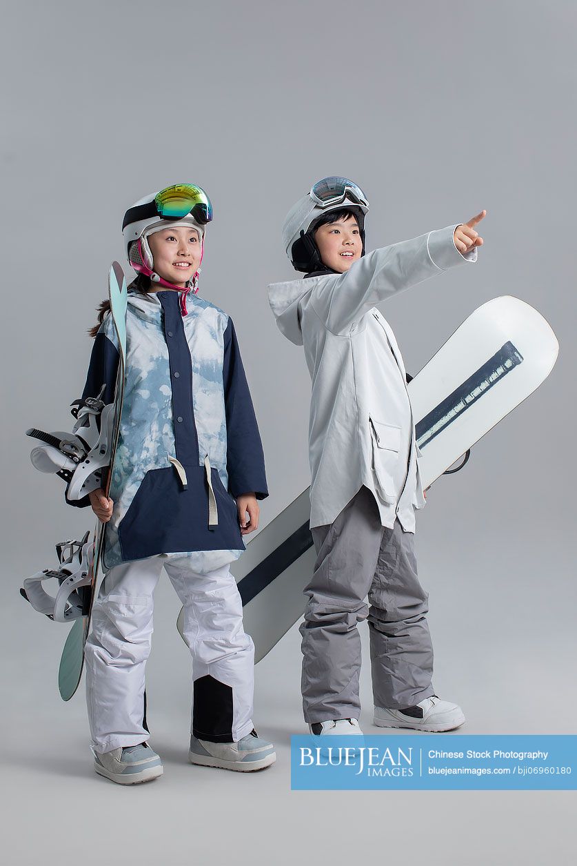 Cheerful Chinese girl and boy with snowboards