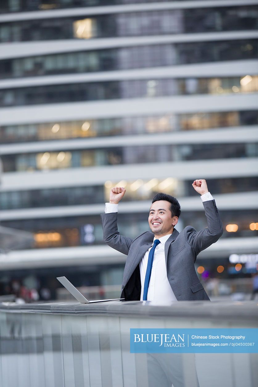 Chinese businessman using laptop outdoors
