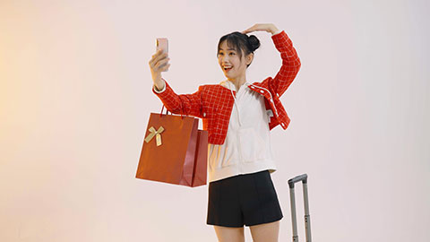 Happy young Chinese woman taking selfie with smart phone