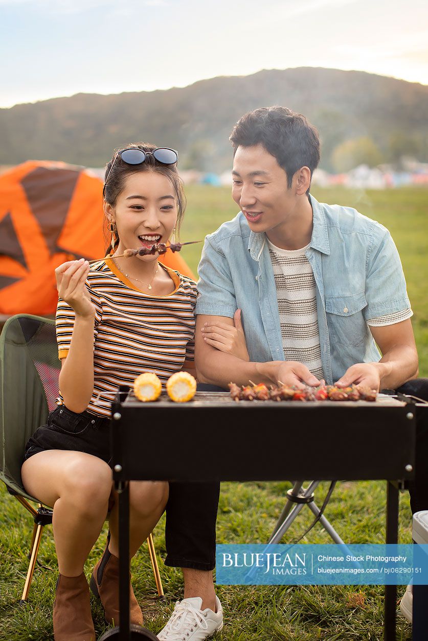 Happy young Chinese couple barbecuing outdoors