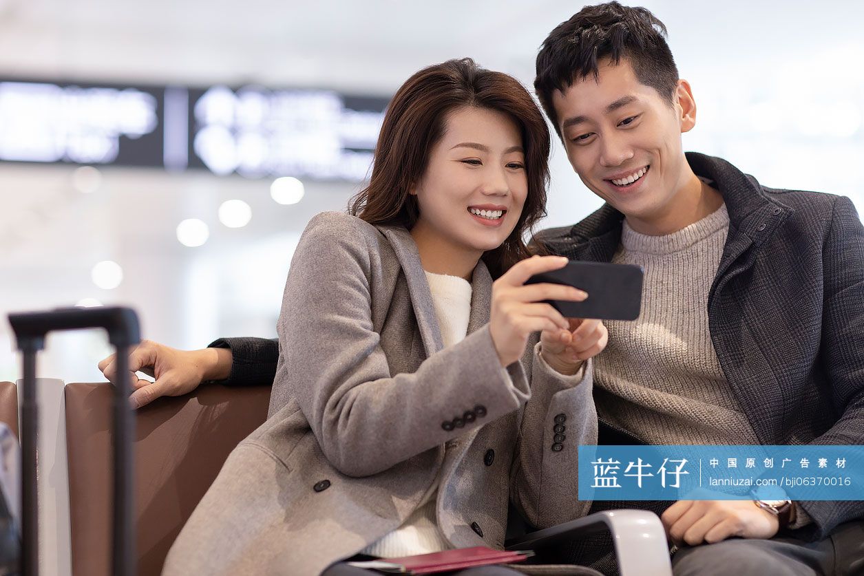 年轻夫妇在机场使用手机