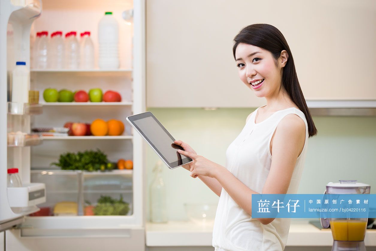 年轻女士在厨房使用平板电脑