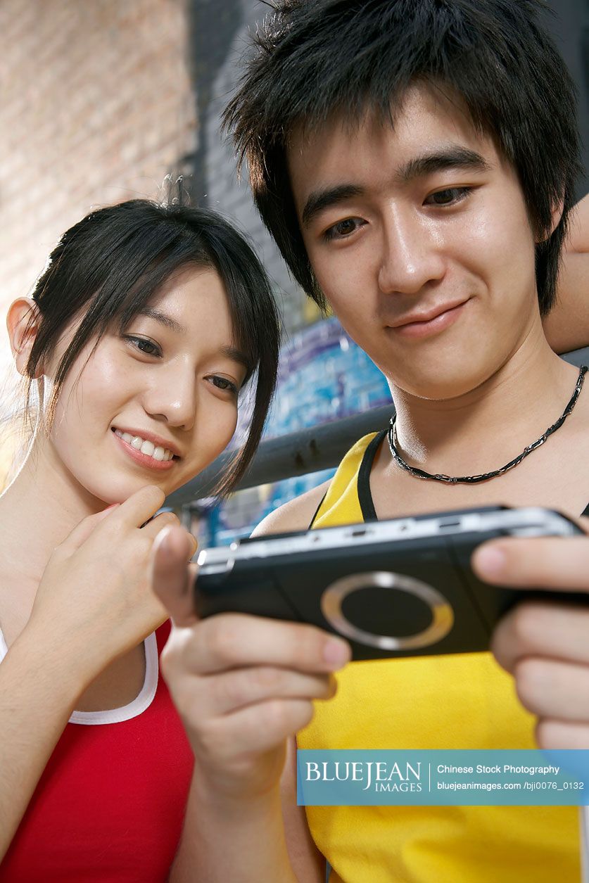 Chinese teenagers playing personal game console