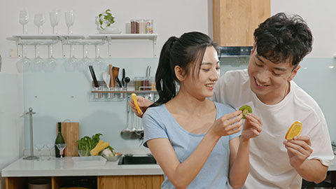 Happy young Chinese couple eating fruit in kitchen,4K