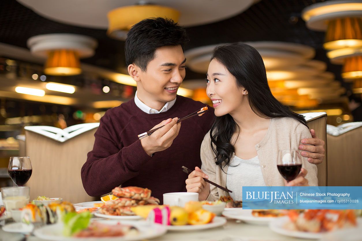 Cheerful young Chinese couple having buffet dinner