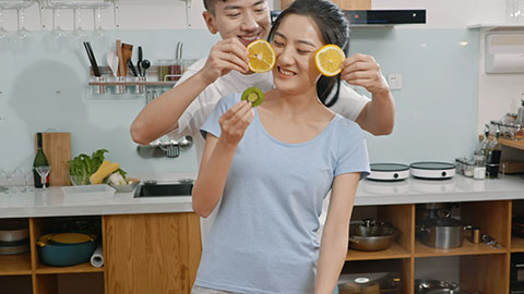 Happy young Chinese couple using juicer in kitchen,4K