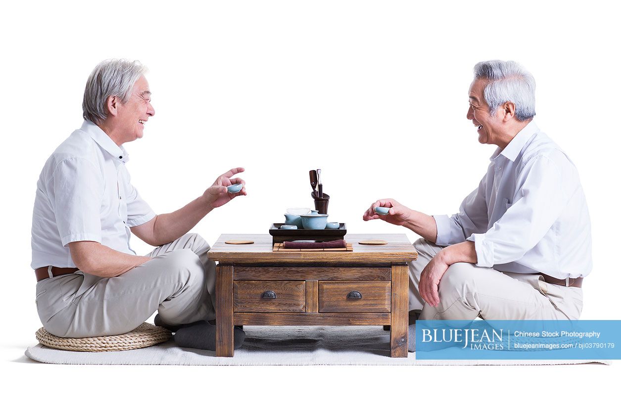 Male senior Chinese friends chatting over tea