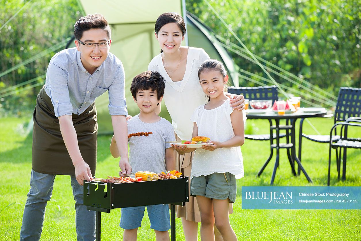 Young Chinese family barbecuing outdoors